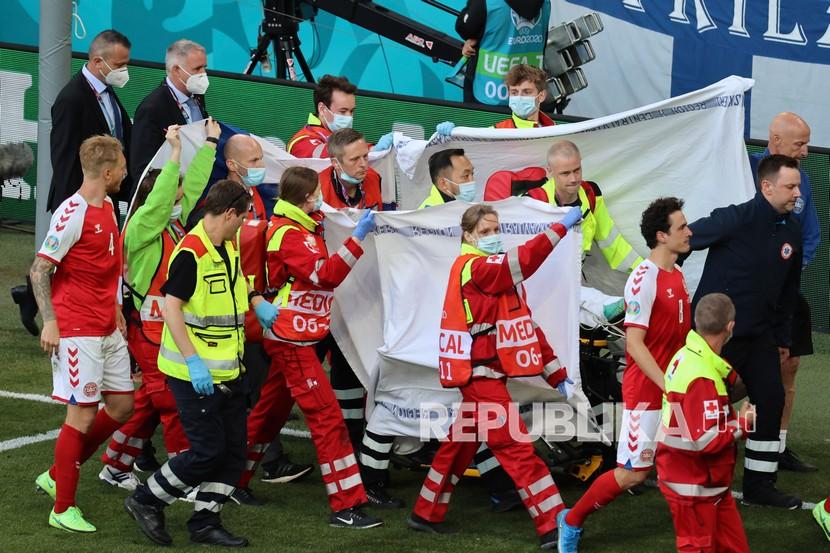 Paramedis menggunakan tandu untuk mengeluarkan Christian Eriksen dari lapangan setelah ia pingsan saat pertandingan grup B kejuaraan sepak bola Euro 2020 antara Denmark dan Finlandia di stadion Parken di Kopenhagen, Denmark, Sabtu (12/6).
