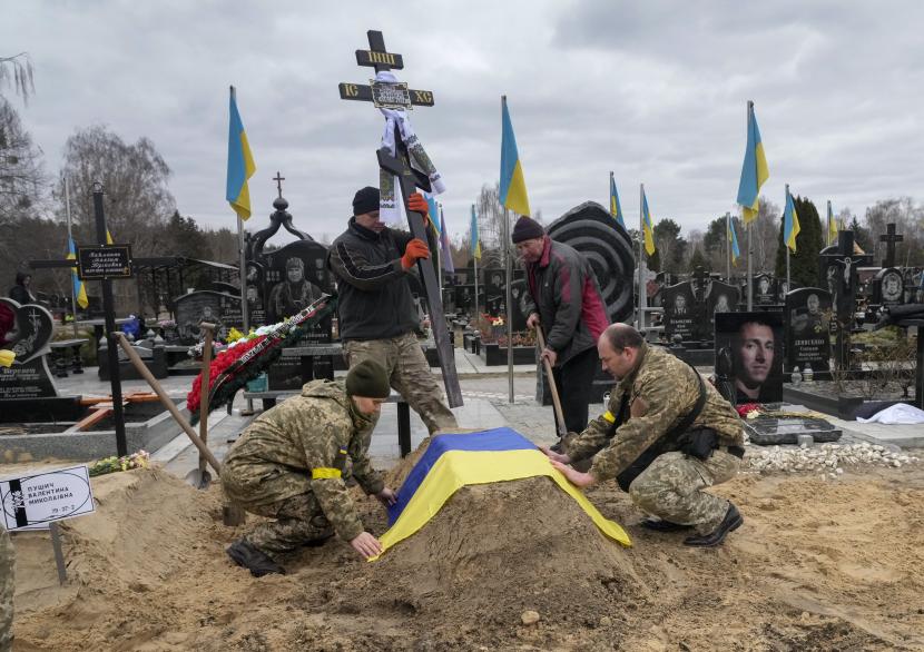 Paramedis Ukraina menutupi dengan bendera Nasional makam rekan mereka Valentyna Pushych yang dibunuh oleh pasukan Rusia di sebuah pemakaman di Kyiv, Ukraina, Sabtu, 5 Maret 2022. 