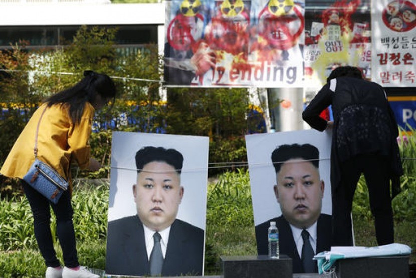 Partisipan memasang foto pemimpin Korea Utara Kim Jong Un dalam demonstrasi menentang uji nuklir dan misil serta HAM tentara perempuan Korut, Selasa, 26 April 2016.