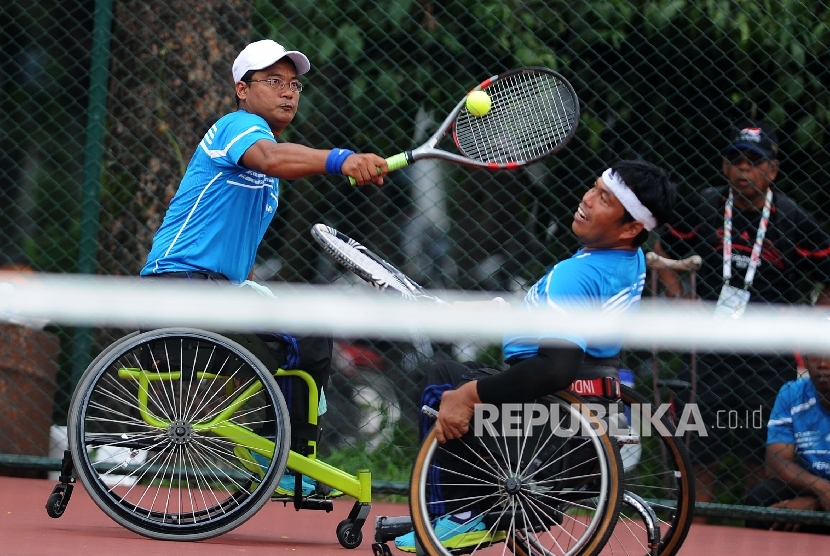 Pasangan atlet paralimpik Yogjakarta Nurdin (kiri) dan Suwardi mengembalikan bola saat pertandingan semifinal tenis ganda putra Peparnas XV 2016 di Lapangan Tenis Siliwangi, Bandung, Sabtu (22/10)