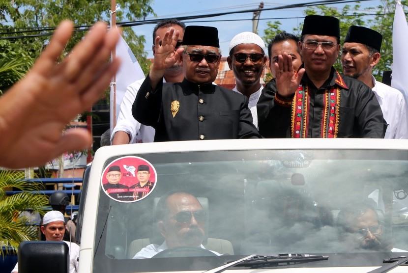 Pasangan bakal calon Gubernur dan Wakil Gubernur Aceh, Zaini Abdullah (kiri) dan Nasaruddin (kanan) melambaikan tangan saat konvoi menuju kantor Komisi Independen Pemilihan (KIP) untuk menyerahkan berkas pendaftaran pencalonan di Banda Aceh, Aceh, Rabu (21