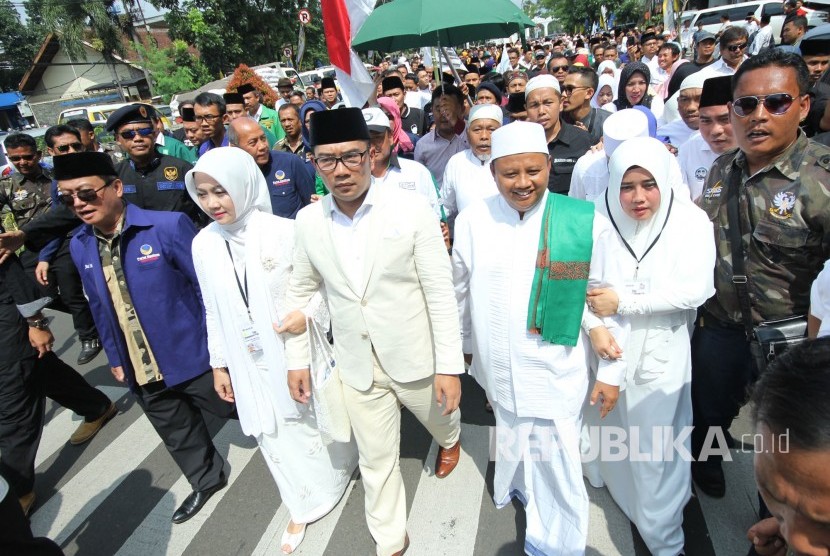 Pasangan calon gubernur dan wakil gubernur Jawa Barat Ridwan Kamil dan Uu Ruzhanul Ulum, bersama istri dan massa pendukungnya berjalan kaki menuju Kantor KPU Jawa Barat, Kota Bandung, Selasa (9/1).