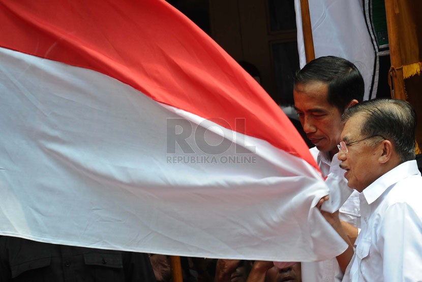   Pasangan Capres-cawapres PDIP Joko Widodo dan Jusuf Kalla mencium bendera merah putih saat deklarasi pasangan capres di Gedung Joang 45, Jakarta, Senin (19/5). (Republika/Tahta Aidilla)