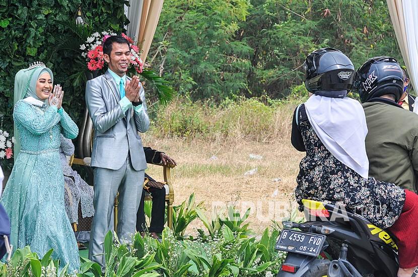 Kewajiban Memenuhi Undangan Walimah Meski Sedang Puasa. Pasangan mempelai saat menyapa tamu pada acara resepsi pernikahan secara drive thru di Bekasi, Jawa Barat.