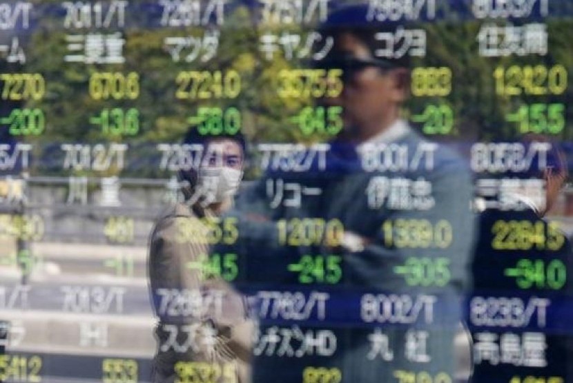 Passers-by are reflected on an electronic stock quotation board outside a brokerage in Tokyo, November 17, 2014.
