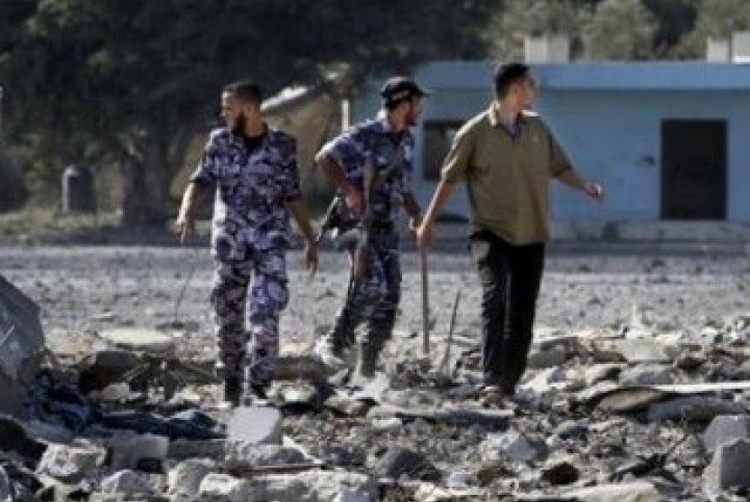 Pasukan keamanan Hamas memeriksa lokasi serangan udara Israel di kota Gaza.