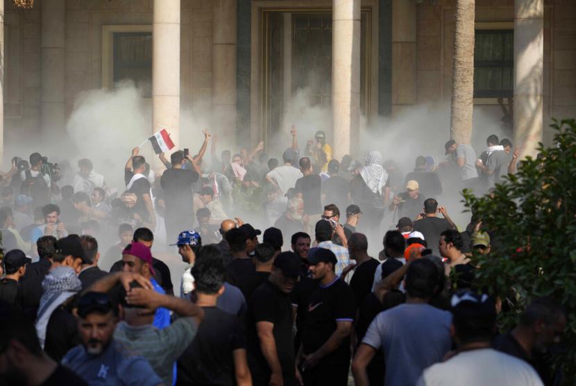 Pasukan keamanan Irak menembakkan gas air mata ke pengikut ulama Syiah Muqtada al-Sadr di dalam Istana pemerintah, Baghdad, Irak, Senin, 29 Agustus 2022. Al-Sadr, seorang ulama Syiah yang sangat berpengaruh mengumumkan dia akan mengundurkan diri dari politik Irak dan pengikutnya yang marah menyerbu istana pemerintah sebagai tanggapan. Kekacauan Senin memicu kekhawatiran bahwa kekerasan bisa meletus di negara yang sudah dilanda krisis politik terburuk dalam beberapa tahun.