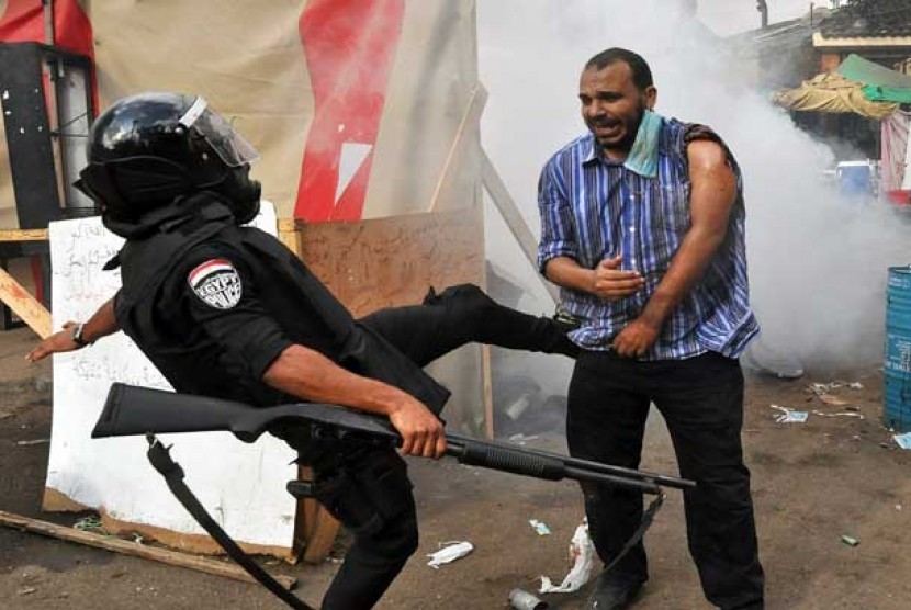  Pasukan keamanan Mesir menendang seorang pengunjuk rasa penentang kudeta militer di Kairo. 