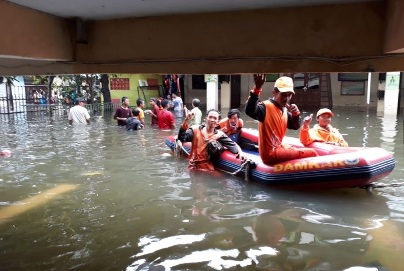 Pasukan oranye yang sedang bertugas di tengah banjir, Jumat (3/1). BNPB mencatat 53 orang meninggal akibat banjir yang melanda Jakarta, Jabar, Banten.