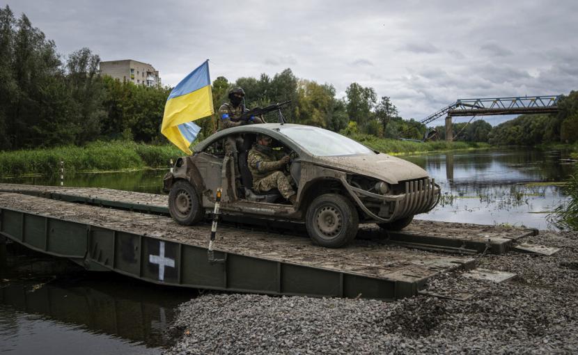 Pasukan terjun payung Ukraina mengendarai kendaraan berbendera Ukraina di jembatan ponton melintasi sungai Siverskiy-Donets di daerah Izium, Ukraina yang baru saja direbut, Rabu, 14 September 2022.