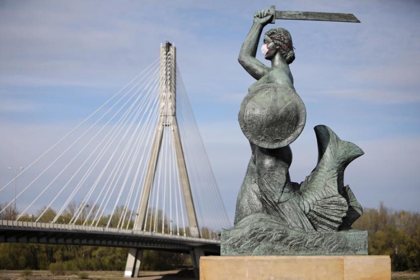 Patung putri duyung di Sungai Vistula, Warsawa, Polandia, tampak mengenakan masker, Sabtu (18/4). Polandia mewajibkan penggunaan penutup mulut dan hidung saat di tempat umum.
