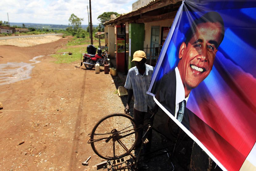   Paul Opiyo Ojwang, pria berusia 43 tahun warga desa Kogelo memasang poster Barack Obama di depan bengkel sepeda miliknya di desa Kogelo, Nyangoma, Kenya, Senin (5/11).     (Reuters/Thomas Mukoya) 