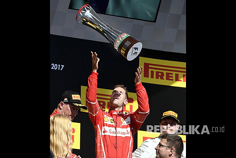 Pebalap Ferrari Sebastian Vettel merayakan kemenangannya pada Grandprix Hongaria di Sirkuit Hongaroring, Hongria, Ahad (30/7).