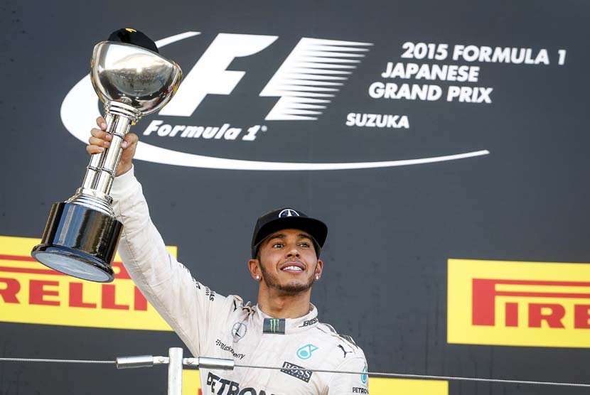 Pebalap Mercedes asal Inggris, Lewis Hamilton, mengangkat trofi usai menjuarai balapan Formula 1 seri GP Jepang di Sirkuit Suzuka, Jepang, Ahad (27/9). 