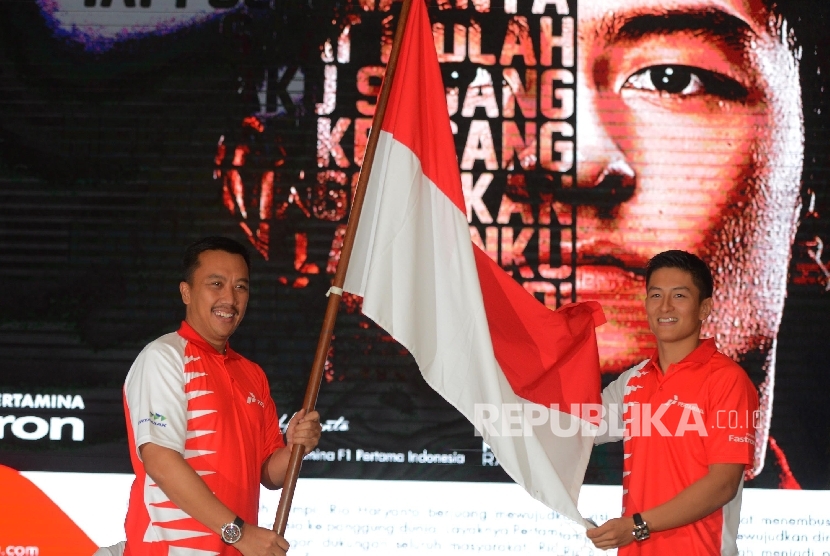  Pebalap Tim Manor Racing Formula 1 Rio Haryanto (kanan), menerima bendera Indonesia dari Menteri Pemuda dan Olahraga Imam Nahrawi (kiri), saat menggelar konferensi pers di Jakarta, Kamis (18/2).