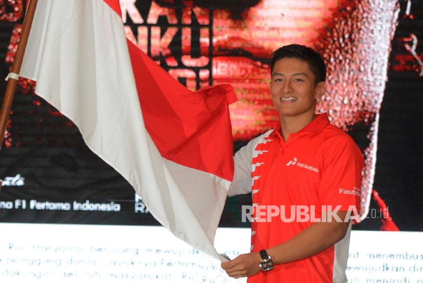  Pebalap Tim Manor Racing Formula 1 Rio Haryanto (kanan), menerima bendera Indonesia dari Menteri Pemuda dan Olahraga Imam Nahrawi (kiri), saat menggelar konferensi pers di Jakarta, Kamis (18/2).