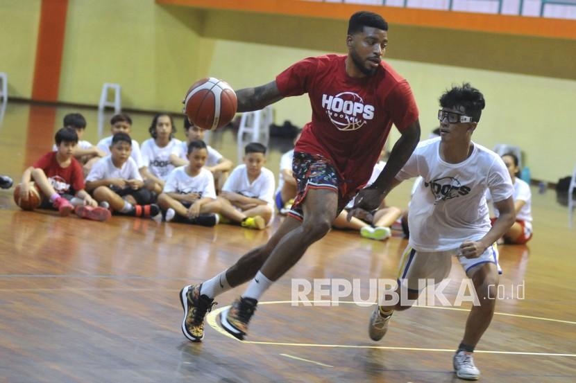 Pebasket Indonesia Jamarr Andre Johnson (kiri) memberikan materi kepada anak-anak peserta pelatihan bola basket di GOR Merpati, Denpasar, Bali, Rabu (23/12/2020). Pelatihan tersebut dilakukan untuk meningkatkan kemampuan sekaligus memberikan motivasi kepada pebasket usia muda.