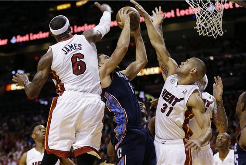 Pebasket Miami Heat, LeBron James (kiri) dan Shane Battier (kanan), memblok pemain Charlotte Bobcats, Jeffrey Taylor (tengah), dalam laga NBA di Miami pada Ahad (24/3). 