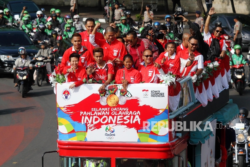   Pebulu tangkis ganda campuran peraih medali emas Olimpiade Brasil, Tontowi Ahmad dan Liliyana Natsir bersama sejumlah atlet dan offsial berada diatas bus tingkat terbuka Bandros menuju Istana Negara di Bundaran HI Jakarta, Rabu (24/8).