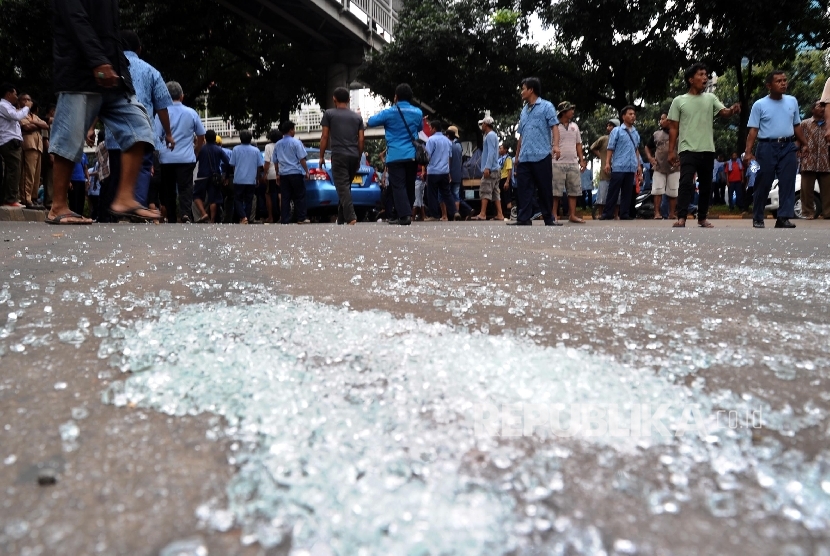 Pecahan kaca mobil berserakan akibat pengerusakan taksi saat demo angkutan umum di Jl Sudirman, Jakarta, Selasa (22/3).