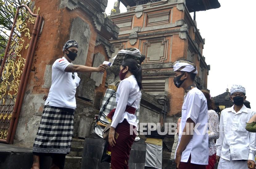 Pecalang atau petugas pengamanan adat Bali memeriksa suhu tubuh umat Hindu yang akan bersembahyang saat Hari Raya Galungan di Pura Jagatnatha, Denpasar, Bali, Rabu (16/9/2020). Perayaan Hari Raya Galungan yang merupakan hari kemenangan kebenaran (Dharma) atas kejahatan (Adharma) tersebut diikuti umat Hindu di Pulau Dewata dengan tetap menerapkan protokol kesehatan secara ketat untuk mencegah penyebaran pandemi COVID-19.