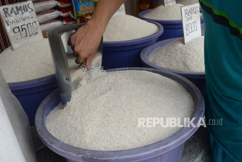 Pedagang beras mengaduk beras di toko miliknya. ilustrasi