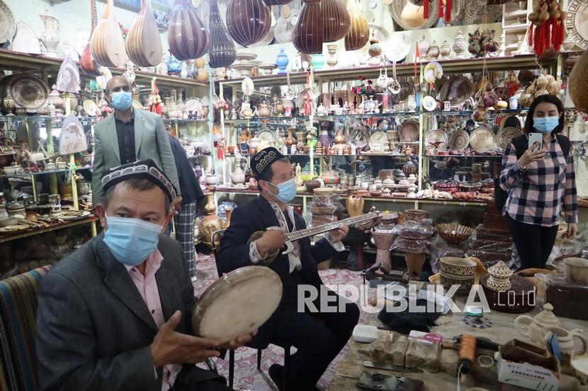 Pedagang cendera mata dari kalangan etnis minoritas Muslim Uighur memainkan alat musik untuk menarik pengunjung di objek wisata Kota Tua Kashgar, wilayah selatan Daerah Otonomi Xinjiang, Cina. 