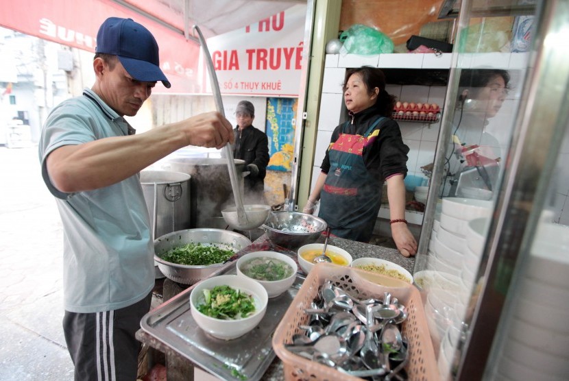 Pedagang kaki lima pho atau sup mi Vietnam sedang meracik semangkuk pho.