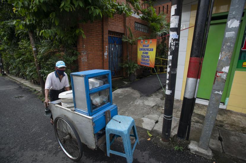 Pedagang keliling melintasi gang perkampungan yang diberlakukan karantina di RT 007/RW 005, Utan Kayu Selatan, Jakarta Timur, Jumat (11/6/2021). Pemberlakuan karantina tersebut dilakukan setelah ditemukannya 22 kasus COVID-19 dari klaster keluarga.