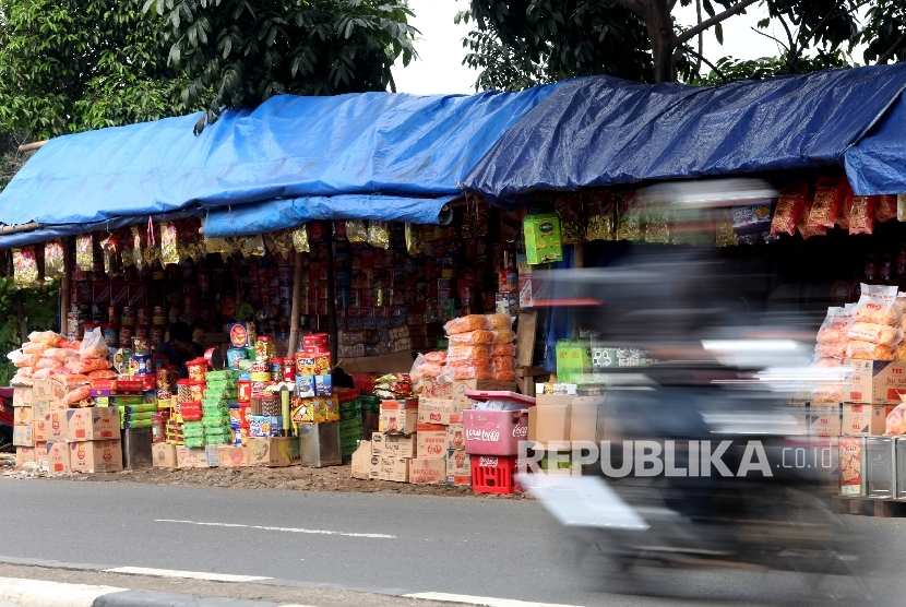 Pedagang Kue menata barang dagangangannya sambil menunggu pembeli di kios semi permanen di Jalan Raya Bogor, Jakarta Timur, Senin (20/6). (Republika/Rakhmawaty La'lang)