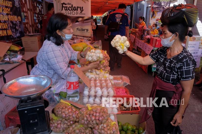 Pedagang melayani warga yang berbelanja saat pasar murah menjelang Hari Raya Idul Fitri 1442 Hijriah di Denpasar, Bali, Selasa (4/5/2021). Kegiatan yang digelar oleh Pemerintah Kota Denpasar pada 4-7 Mei 2021 tersebut untuk meringankan beban ekonomi masyarakat dalam memperoleh bahan pokok dengan harga yang lebih murah dari harga di pasaran.