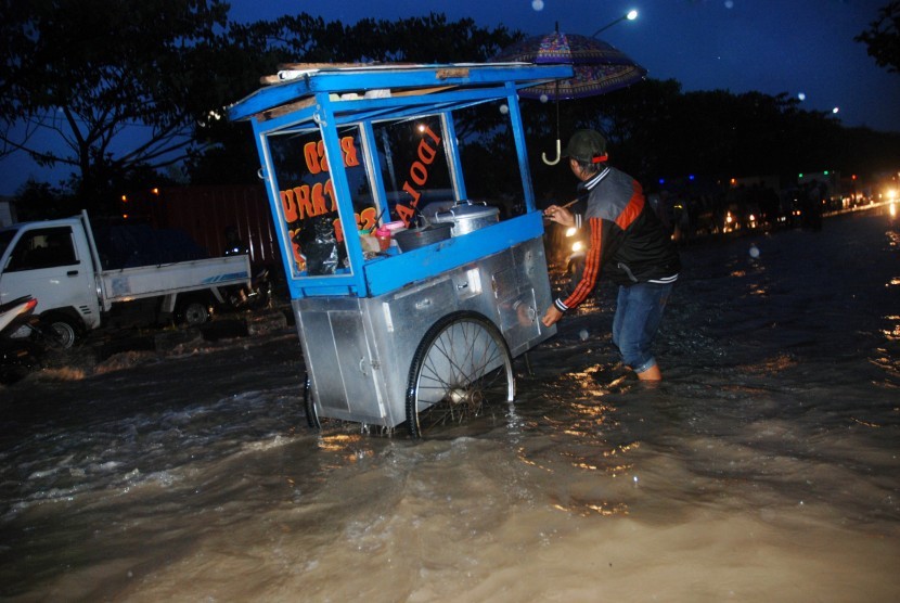 Pedagang melewati banjir di Gedebage, Bandung, Jawa Barat, Jumat (28/10). 