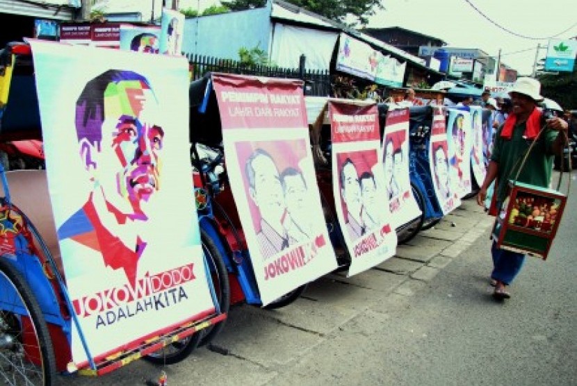 Pedagang melintas di barisan becak bergambar Capres Joko Widodo, di Jl Prabu Siliwangi, Pamulang,Tangerang Selatan, Banten, Sabtu (7/6).