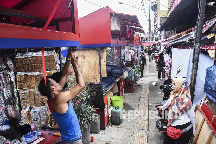 Pedagang memasang karung plastik di lapak barunya di kawasan Pasar Cicadas, Kota Bandung, Selasa (27/8). 