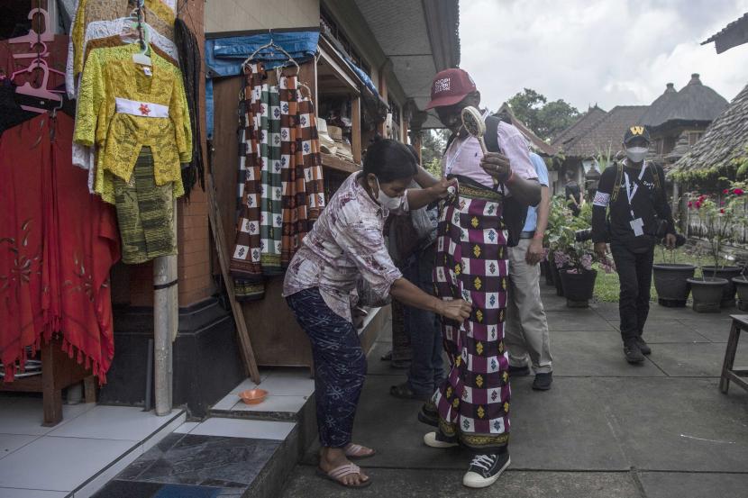 Pedagang membantu wisatawan mengenakan pakaian adat Bali di Desa Penglipuran, Bali, Sabtu (28/5/2022) (ilustrasi). PT Bank Central Asia Tbk menyalurkan kredit di sektor pariwisata sekitar Rp 14 triliun pada April 2022. 
