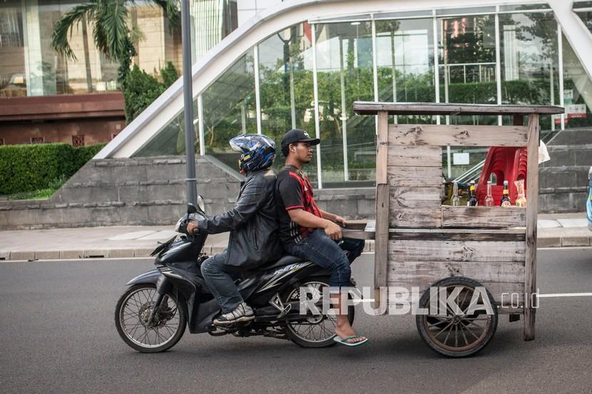 Pedagang membawa gerobak dengan sepeda motor di kawasan Dukuh Atas, Jakarta. Tanpa anggaran PEN, Bank Dunia mengestimasi angka kemiskinan Indonesia pada 2020 mencapai 11,8 persen. Hal ini artinya program PEN telah mampu menyelamatkan lebih dari lima juta orang dari kemiskinan sepanjang 2020.