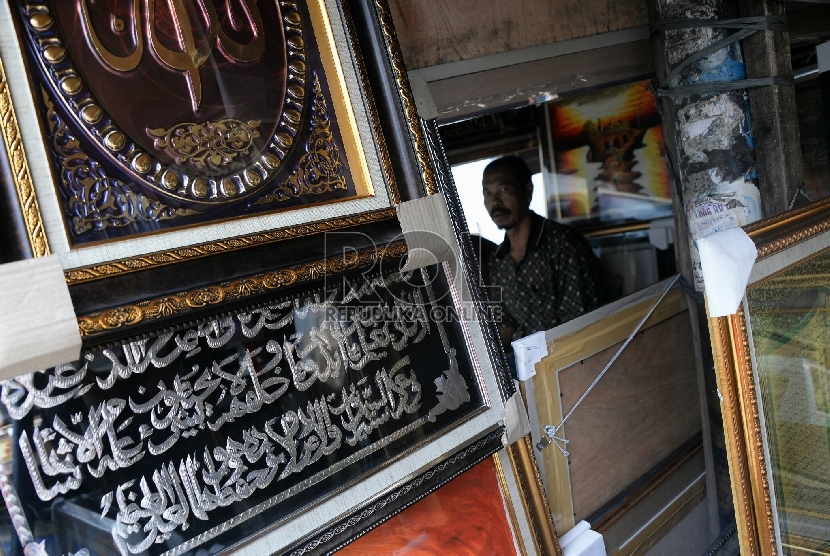 Pedagang memberishkan hiasan kaligrafi dinding di Kawasan Pasar Baru, Jakarta, Kamis (30/7). 