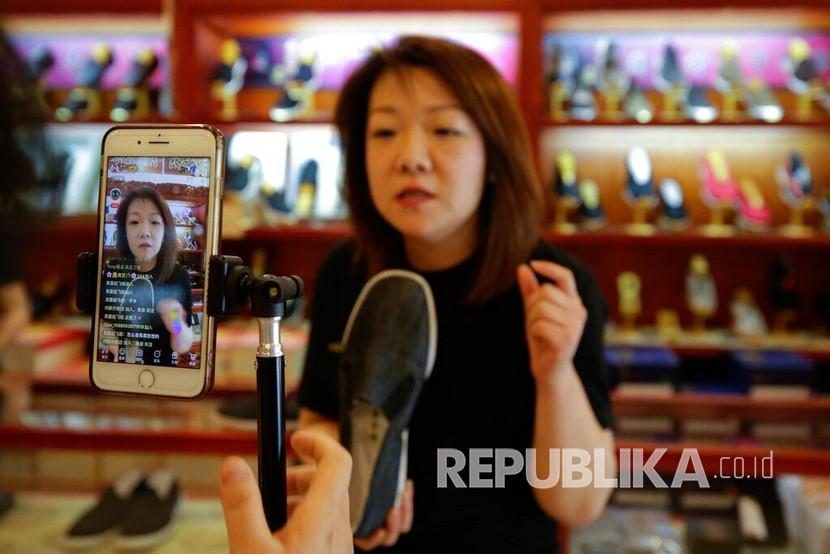 Pedagang menawarkan sepatu kepada pelanggannya melalui siarang langsung di Neiliansheng Footwear di Beijing, Cina, Selasa (28/4).Sejumlah pedagang  di Cina menggunakan siaran langsung untuk menawarkan produknya ke pelanggan ditengah pandemi COVID-19. Melalui siaran langsung secara daring pedagang dapat berinteraksi dengan pelanggan secara langsung sekaligus melakukan transaksi. 