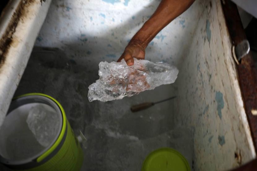 Pedagang mengambil bongkahan es batu dari freezer. Es batu tak semuanya terbuat dari air matang. 