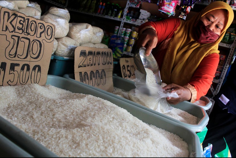 Pedagang mengemas beras pesanan pelanggannya di salah satu agen.