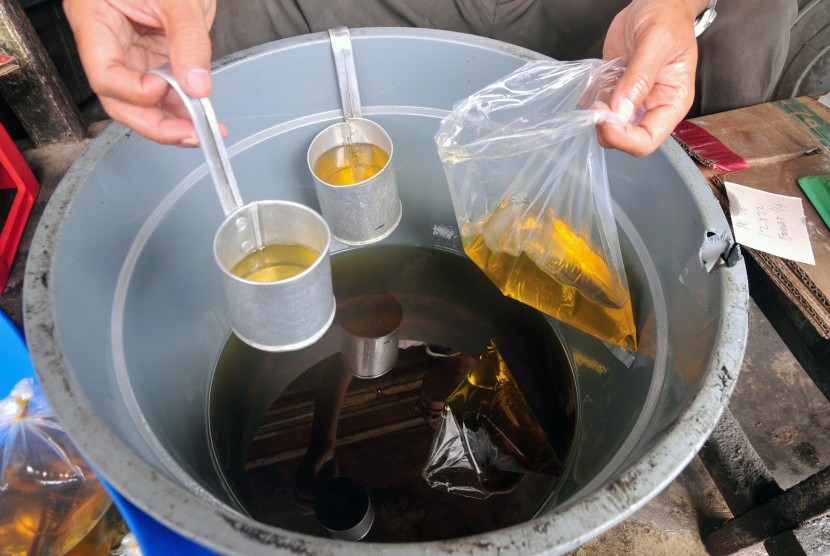 Pedagang mengemas minyak goreng curah di pasar tradisional.