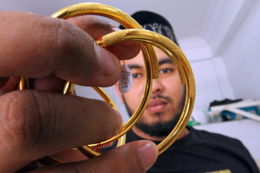 Pedagang menunjukkan perhiasan gelang emas di Lhokseumawe, Aceh, Jumat (10/9). Harga emas anjlok lebih dari dua persen pada akhir perdagangan Senin (22/11), tertekan dolar AS.