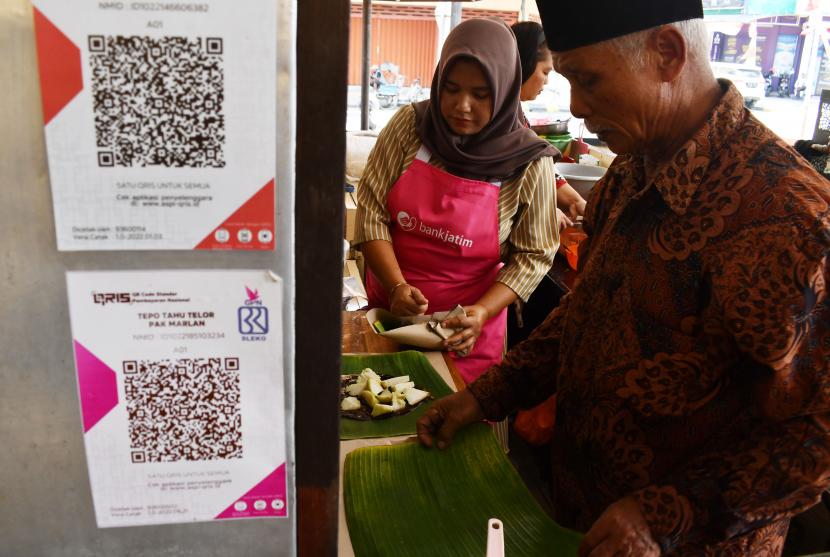 Pedagang menyiapkan sajian makanan yang dipesan pengunjung di sebuah stan yang telah melayani pembayaran dengan metode scan Quick Response Code Indonesian Standard (QRIS) saat peluncuran Pasar Sleko sebagai pasar siap QRIS di Sleko Food Court Kota Madiun, Jawa Timur, Jumat (19/8/2022). Peluncuran QRIS di pasar tersebut oleh Bank Indonesia bersama Pemkot setempat sebagai upaya mendorong digitalisasi pembayaran guna mempermudah transaksi nontunai.