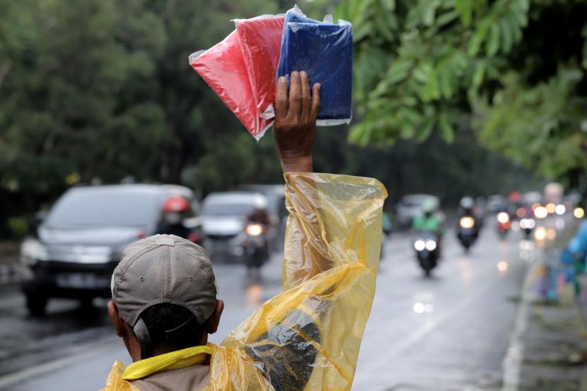 Pedagang musiman menawarkan jas hujan kepada pengendara yang melintas di Surabaya, Jawa Timur, Kamis (6/1/2022). Cuaca Hari Ini: BMKG Peringatkan Potensi Hujan Lebat di Sejumlah Wilayah