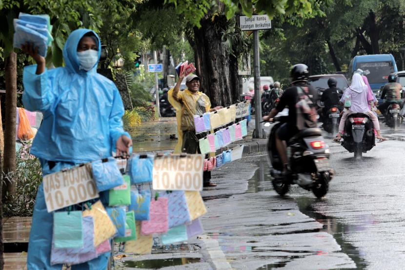 Pedagang musiman menawarkan jas hujan kepada pengendara yang melintas di Surabaya, Jawa Timur, Kamis (6/1/2022). BMKG: Sebagian Jatim Memasuki Musim Hujan Lebih Awal