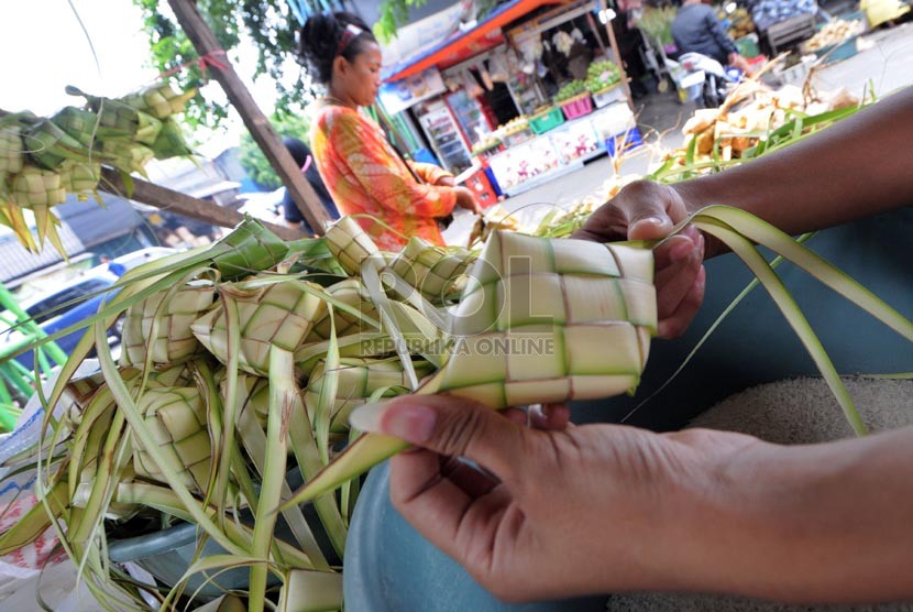   Pedagang musiman merangkai janur kelapa menjadi ketupat untuk dijual di Jalan Raya Bogor, Jakarta, Senin (14/10).  (Republika/Aditya Pradana Putra)