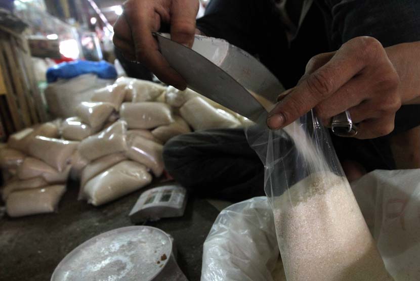 Pedagang saat menimbang gula pasir di pasar tradisional.
