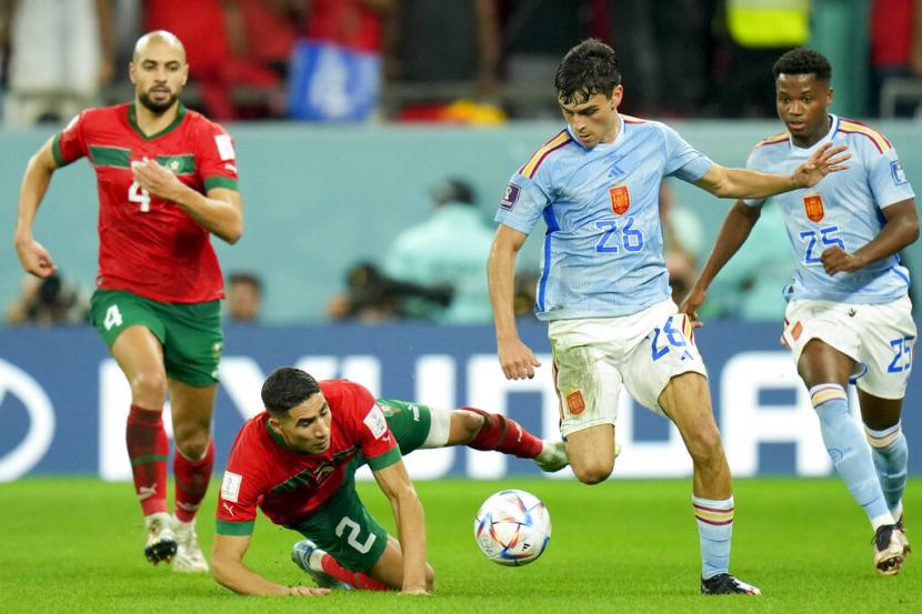  Pedri dari Spanyol (kanan) dan Achraf Hakimi dari Maroko bertarung memperebutkan bola pada pertandingan sepak bola babak 16 besar Piala Dunia antara Maroko dan Spanyol, di Education City Stadium di Al Rayyan, Qatar, Selasa, 6 Desember 2022.