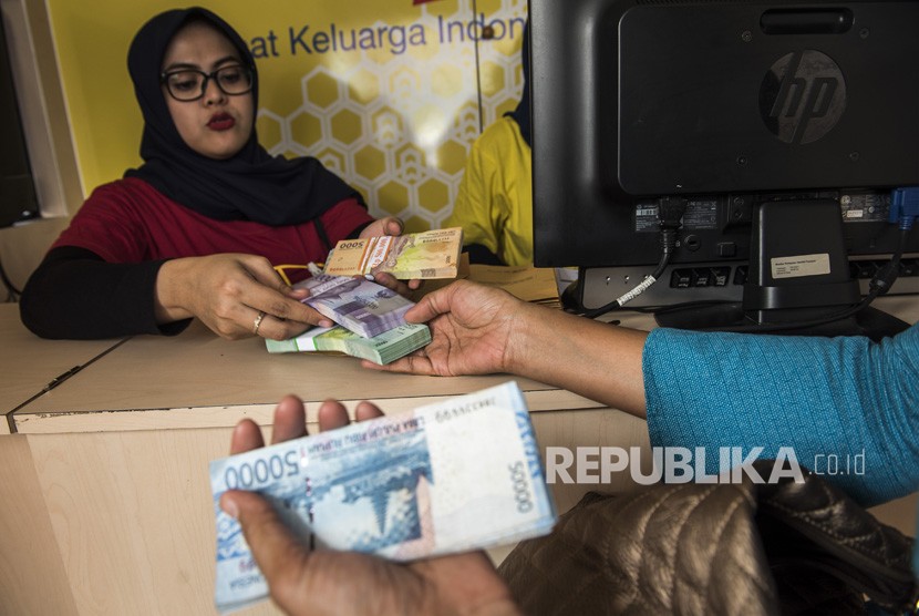 Pegawai bank melayani warga yang menukarkan uang