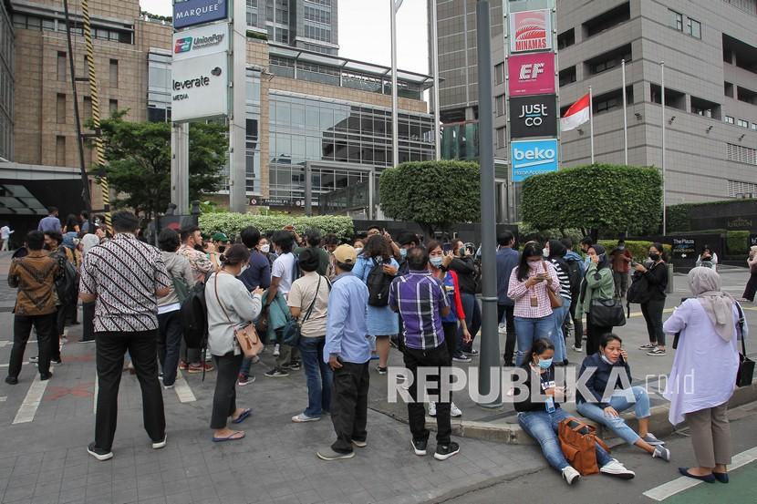 Pegawai berhamburan keluar gedung setelah merasakan gempa di kawasan perkantoran Jl. M.H. Thamrin, Jakarta, Jumat (14/1/2022). Guncangan gempa berkekuatan magnitudo (M) 6,7 di wilayah Banten terasa hingga Jakarta.